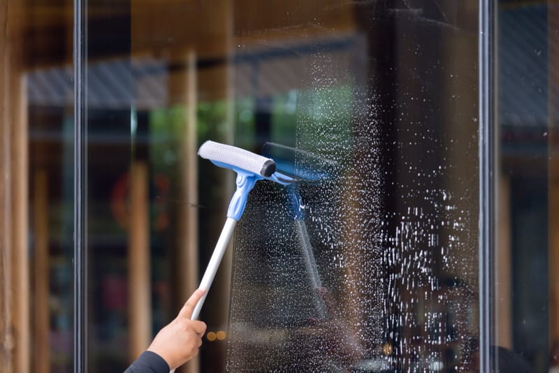 Professional window cleaner washing glass with a squeegee